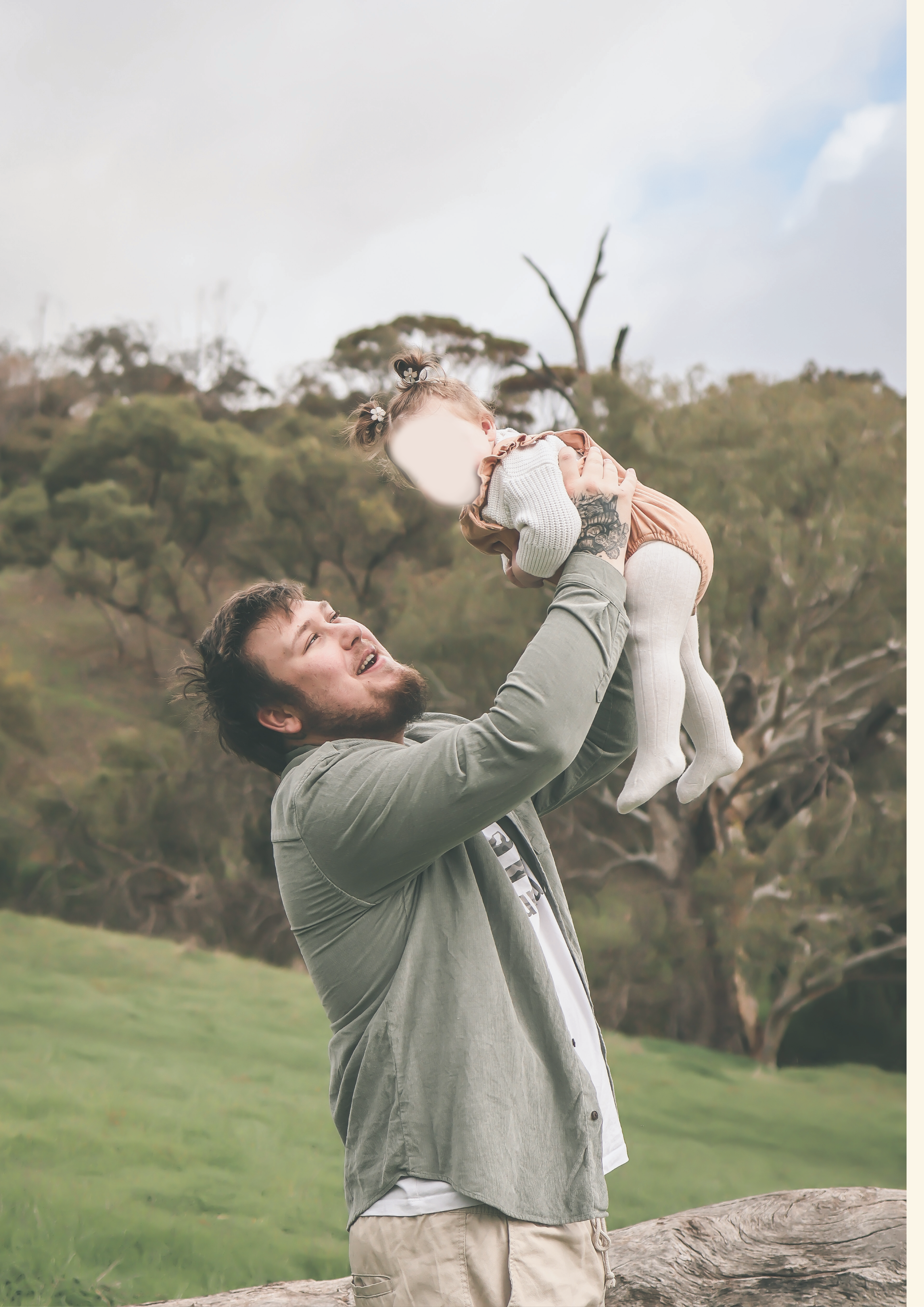 Man holding a baby high up in the air with a natural background